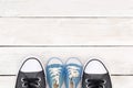 Daddy`s boots and baby`s sneakers, on white wooden background, f Royalty Free Stock Photo